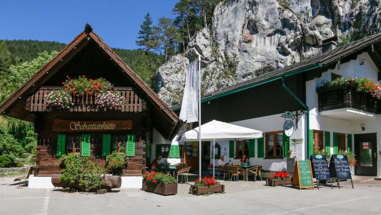 Ein traditionelles Gasthaus mit Holzbalkon und Blumenschmuck vor einer Felswand.
