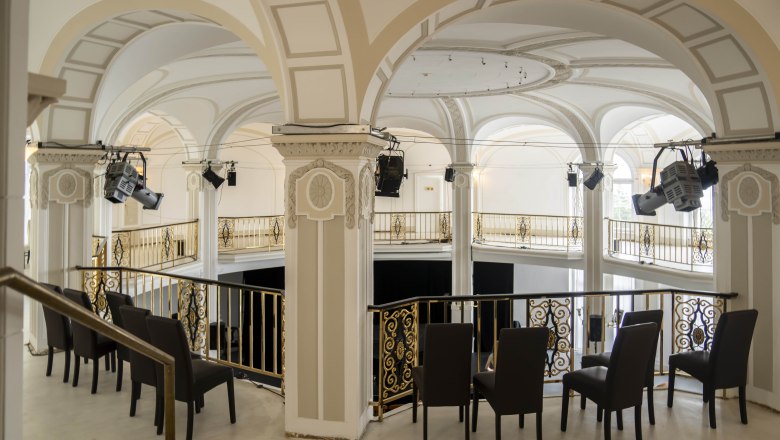 Innenansicht eines eleganten Saals mit B&ouml;gen und goldenen Gel&auml;ndern.