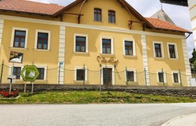 Gelbes Geb&auml;ude mit der Aufschrift 'Villa Luef', umgeben von einem Zaun und einer Stra&szlig;e im Vordergrund.