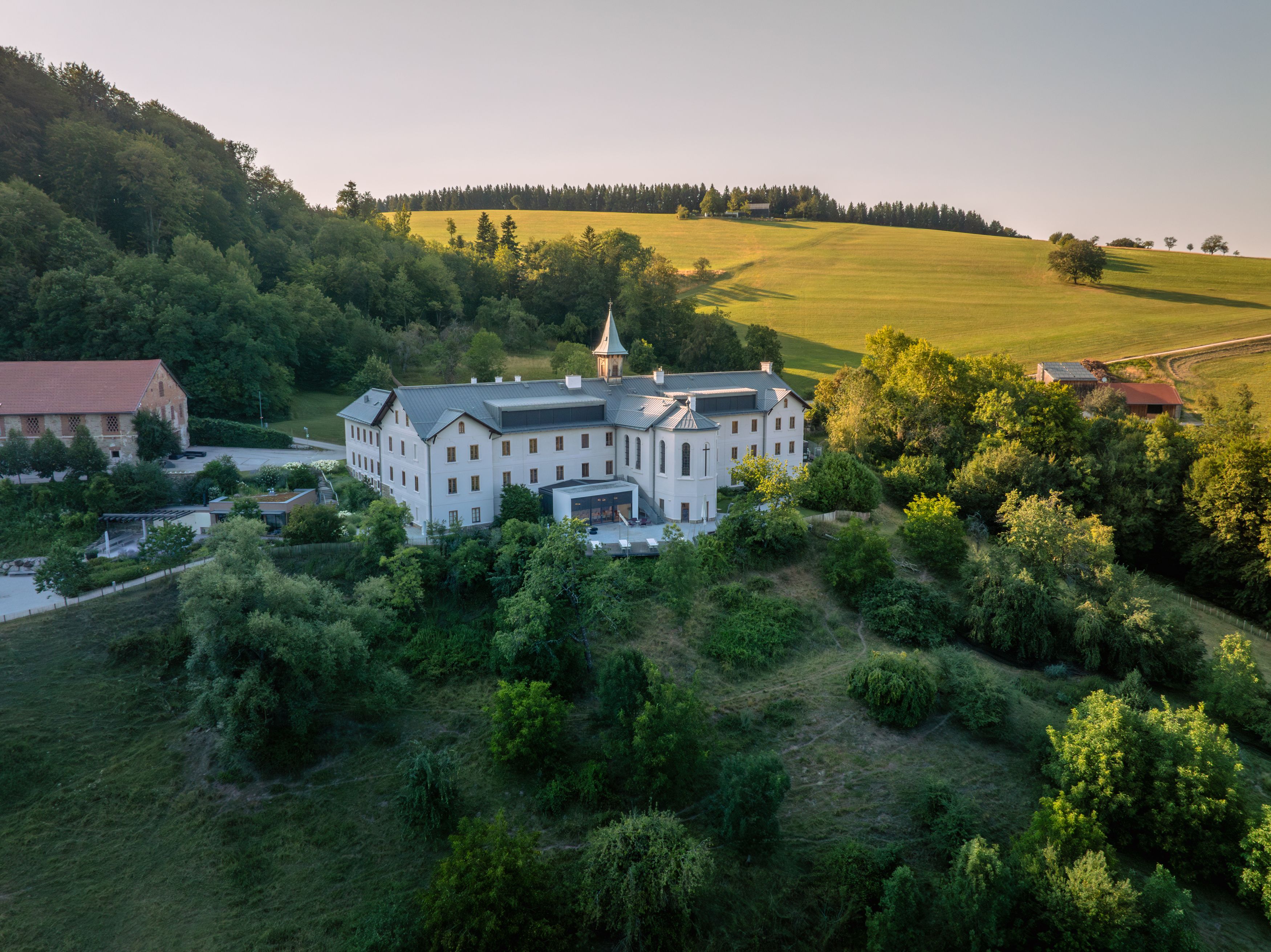 Luftaufnahme eines großen weißen Gebäudes in einer grünen Landschaft.