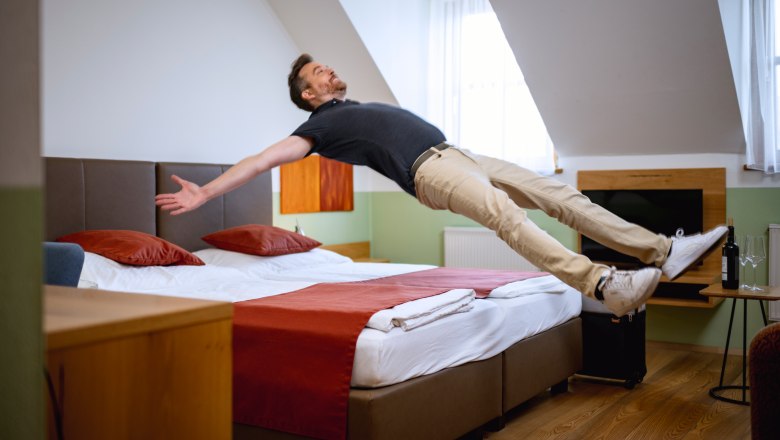 Doppelzimmer Weingut & G&auml;stezimmer Edelmann, Mann springt auf Bett